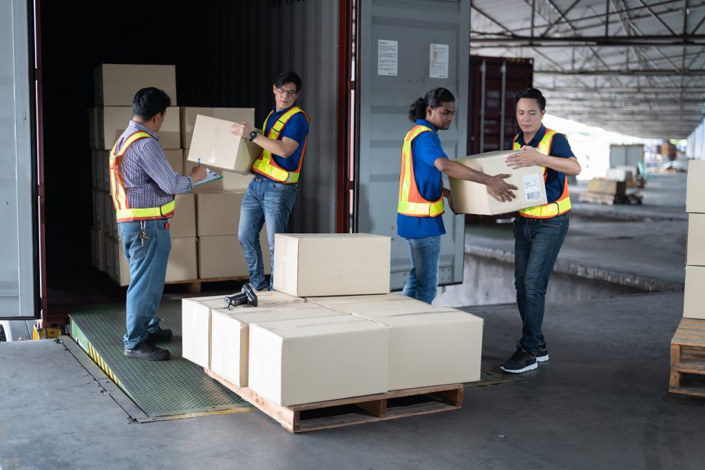 4 men Warehouse worker open doors steel 40 feet container and help carry box one by one supervisor stand near by using paper clip checklist